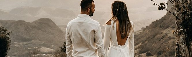 older man and woman facing each other, looking away holding hands