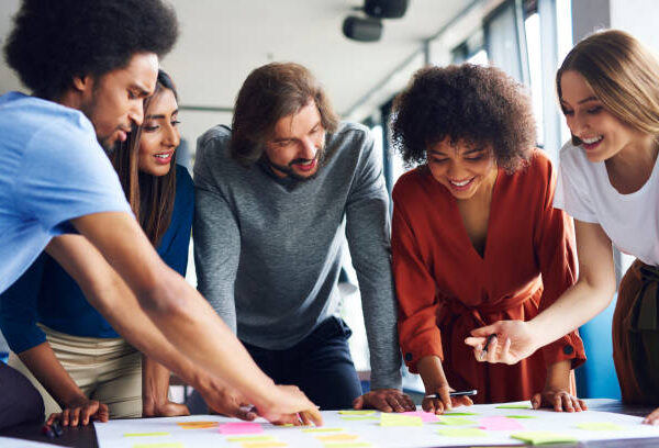 Creative Entrepreneurs standing around each planning Memberships for their online business while hovering over a group table