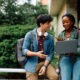 2 Entrepreneurs and students sit outside on a laptop discussing eLearning