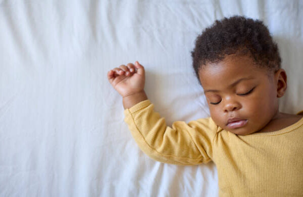 a baby girl lying on bed asleep